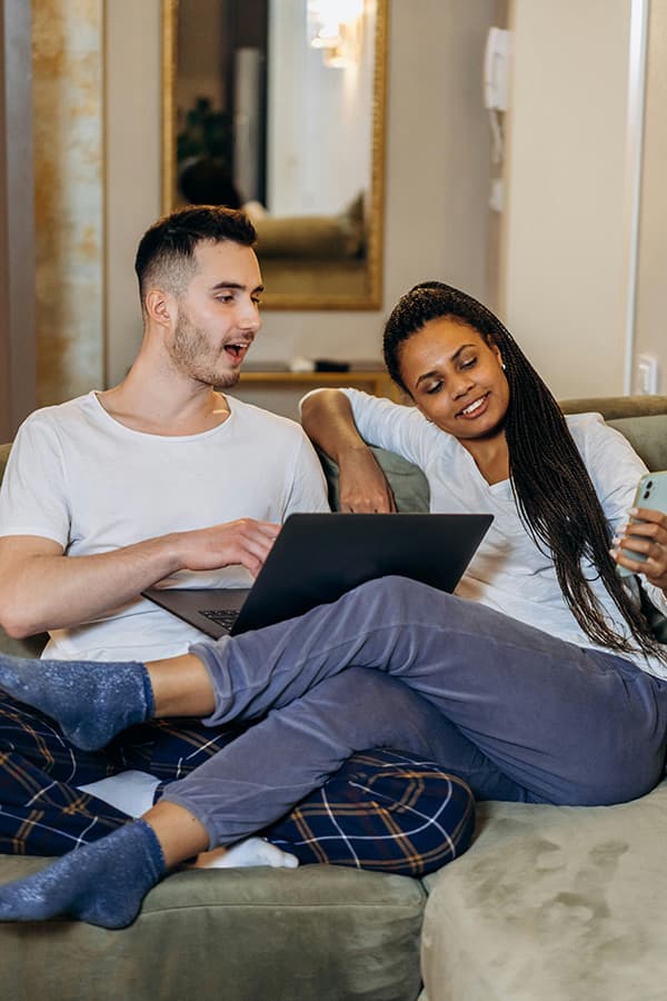 couple sitting on couch looking at devices